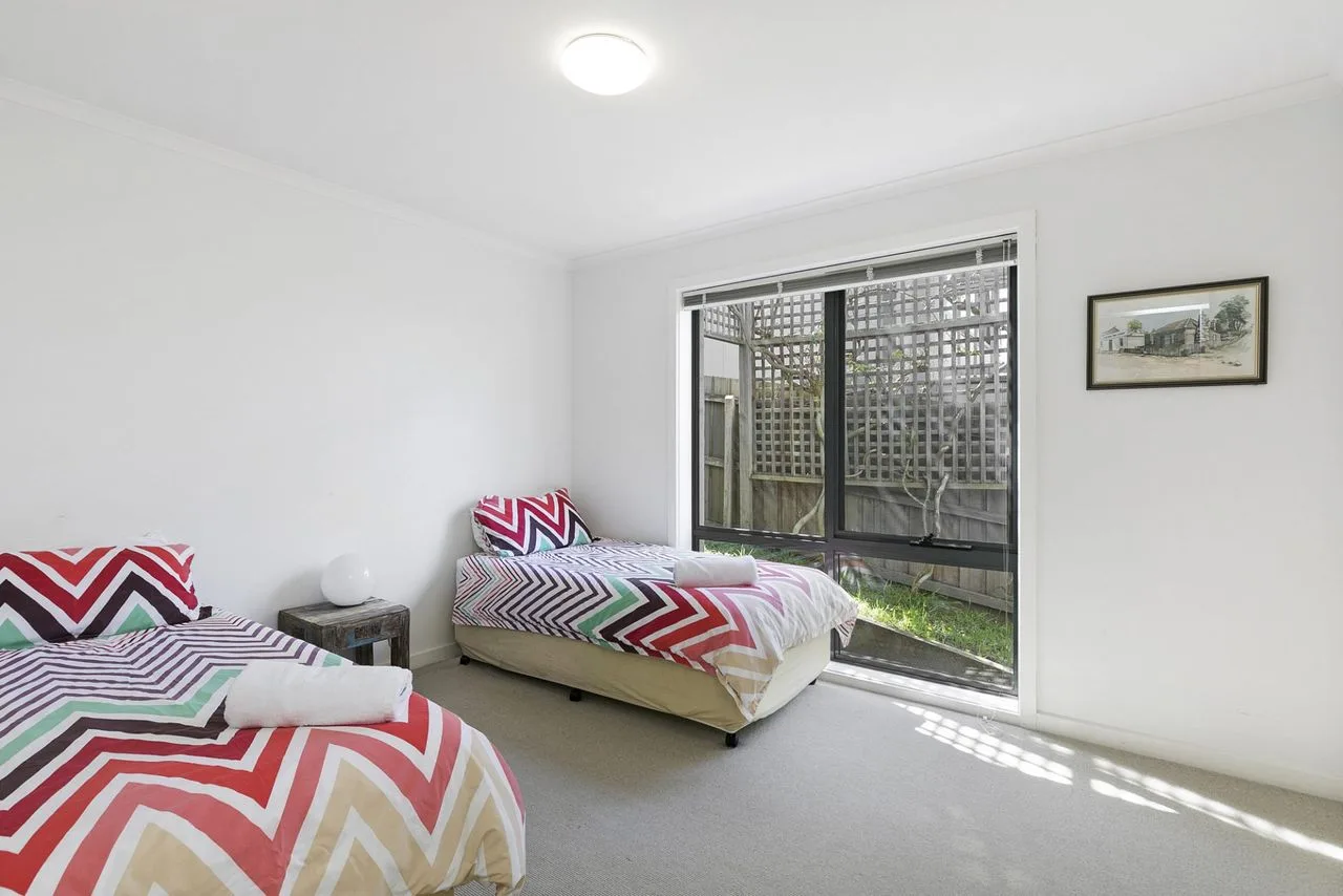 A bedroom with two beds and a sliding glass door opening onto a small patio.