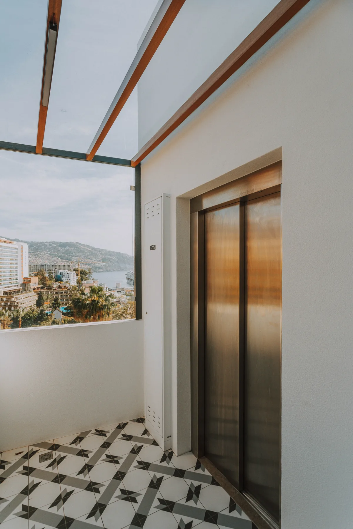 Un vestíbulo de ascensor con puertas metálicas y una gran ventana con vistas a la ciudad.