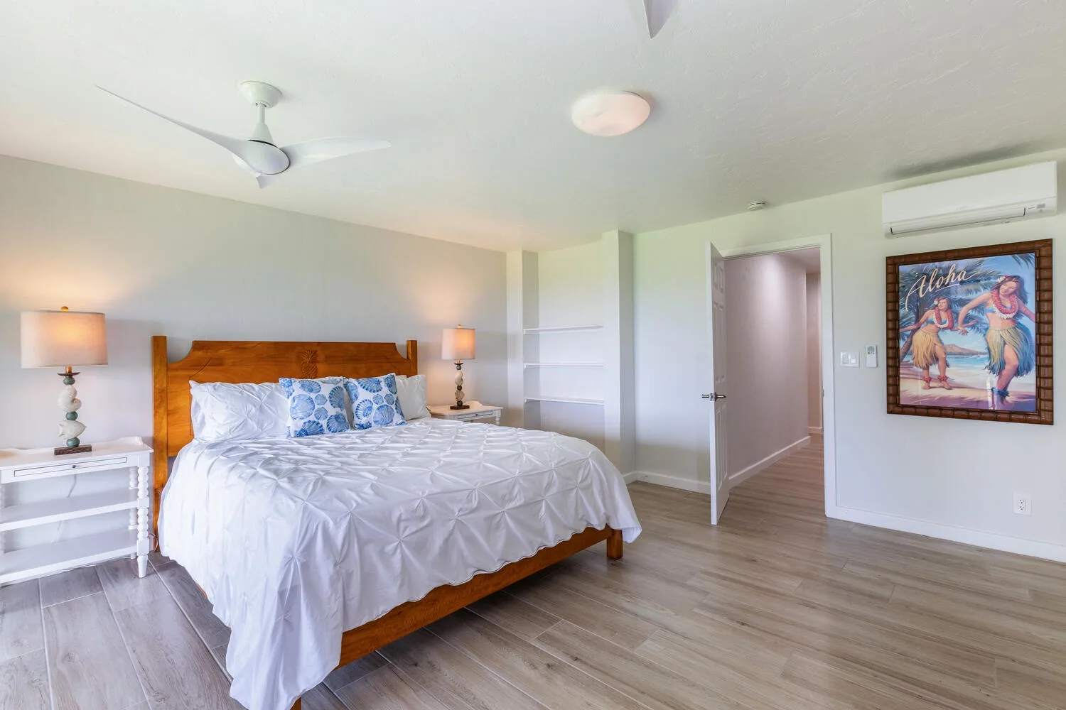 Un dormitorio con una cama de madera, ropa de cama blanca y un ventilador de techo.