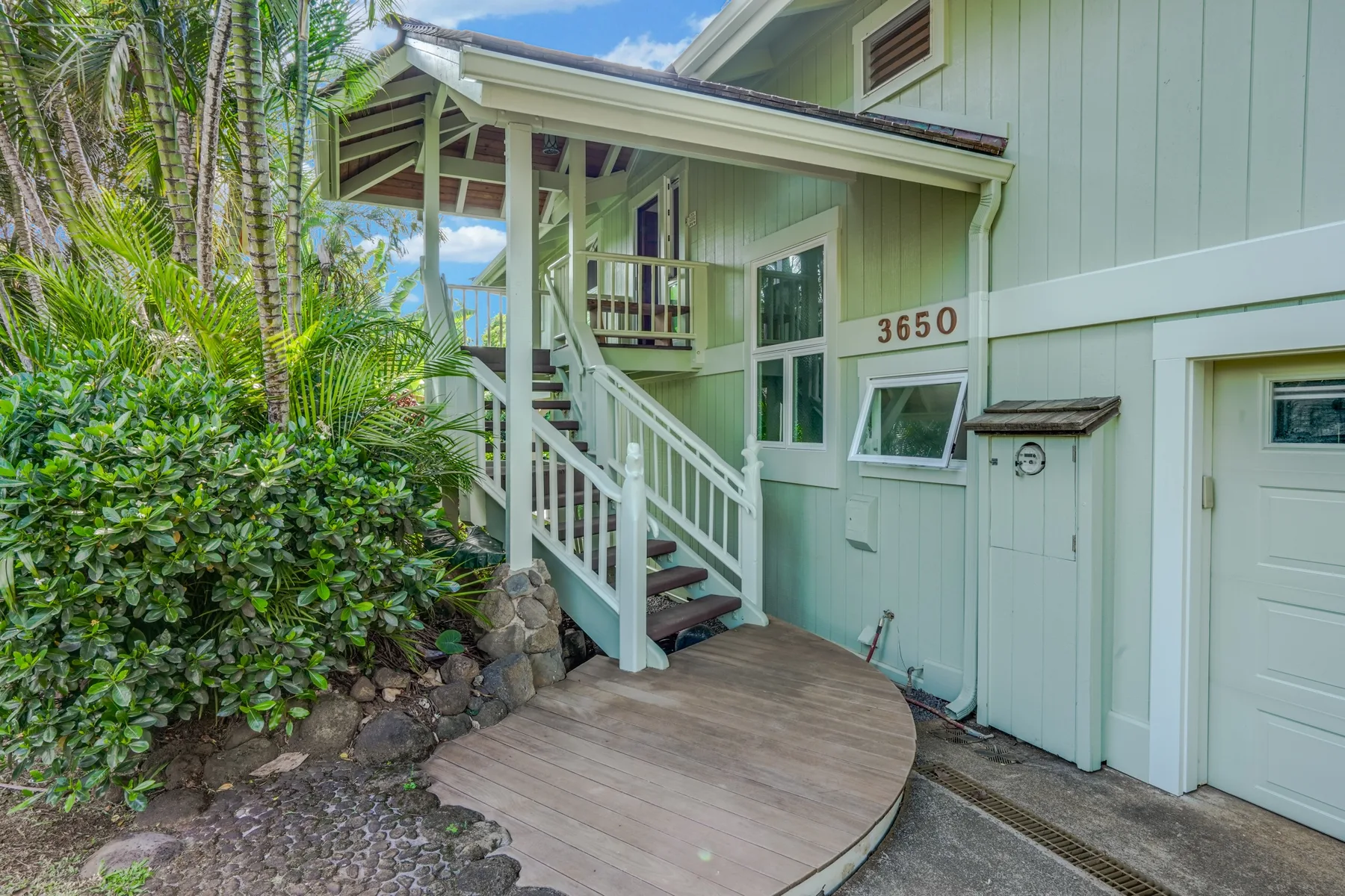 Entrada de una casa verde pálido con un pequeño porche de madera y escalones.