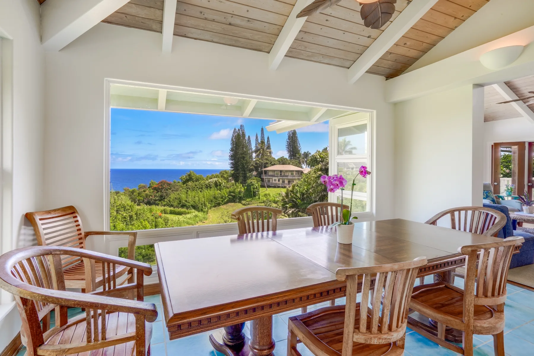 Un comedor con mesa y sillas de madera junto a una amplia vista al océano.