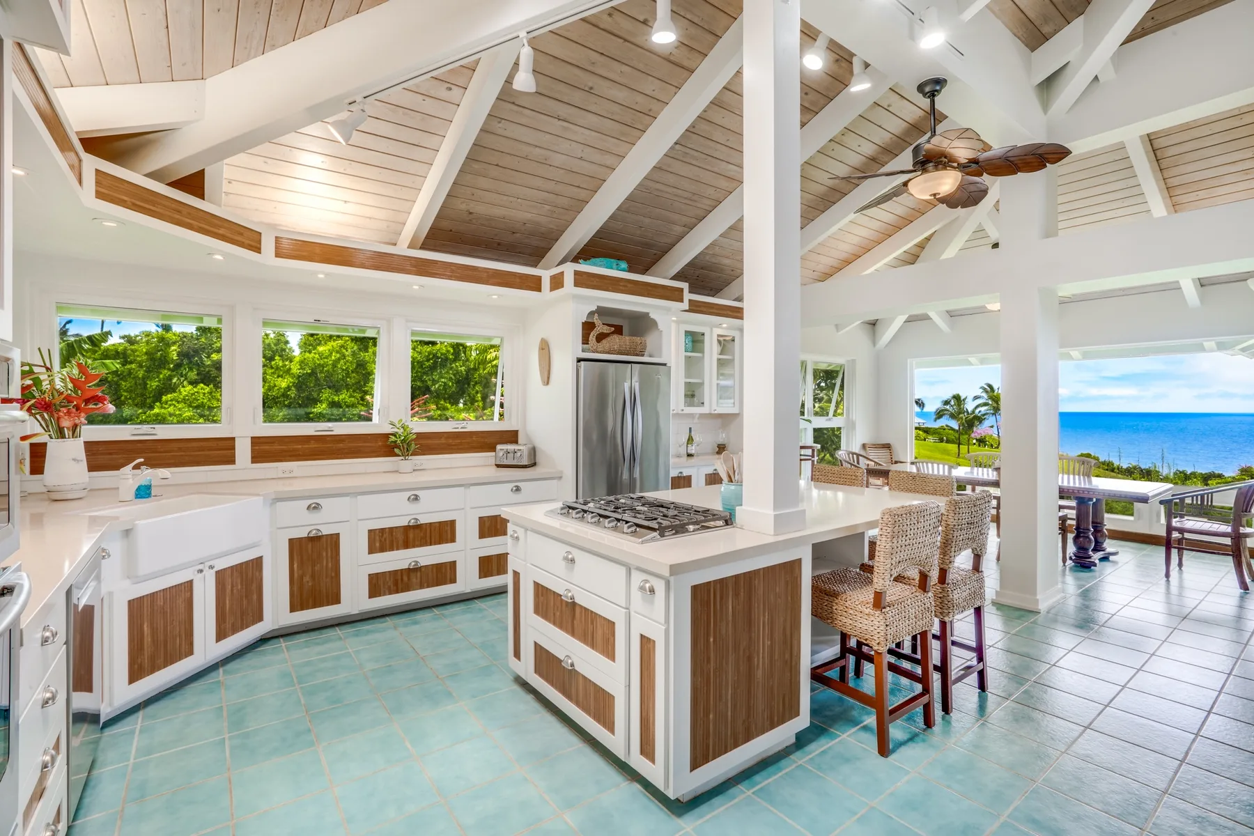 Una cocina luminosa y abierta, con una isla central y vistas al mar por las ventanas.
