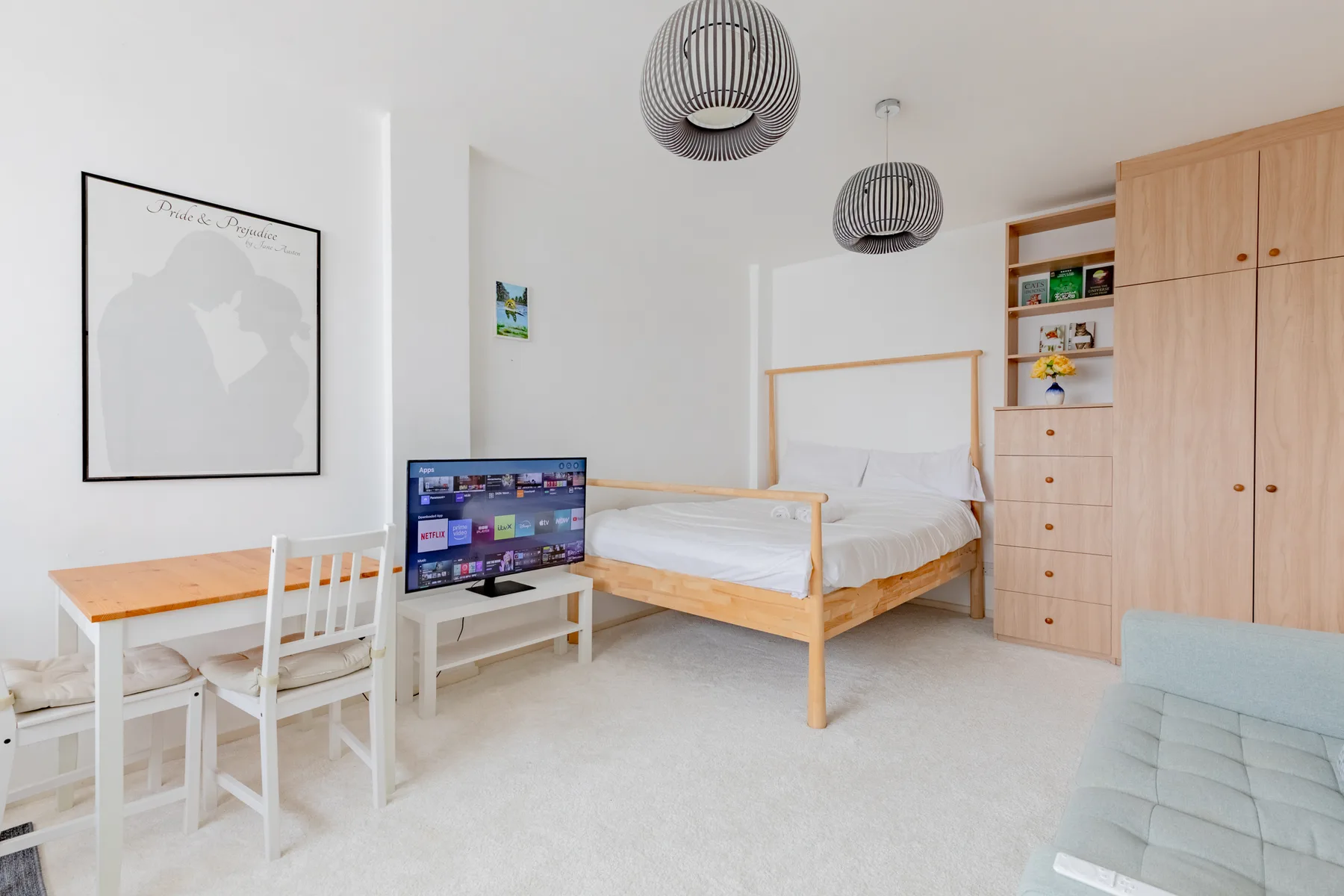 A bright bedroom with a wooden bed, desk, and television.