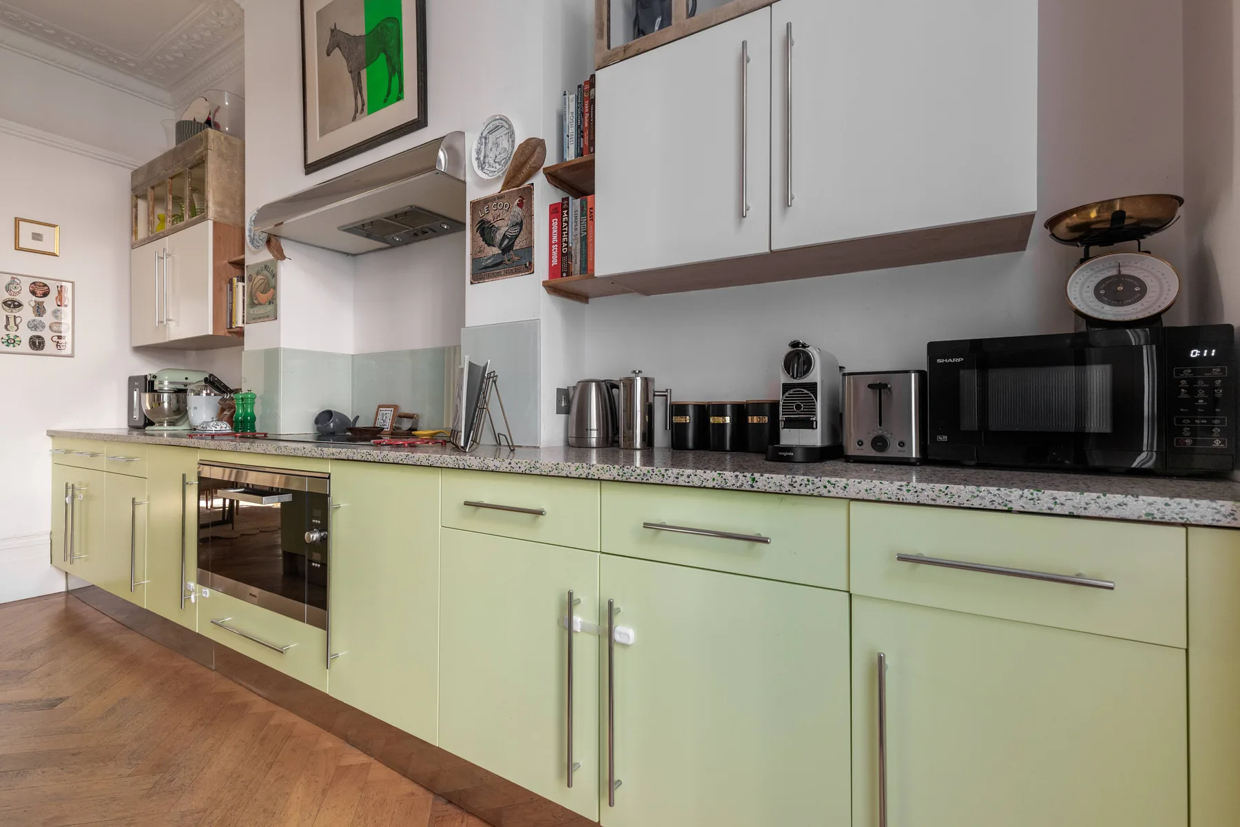 A kitchen with pale green cabinets, a countertop, and several small appliances.