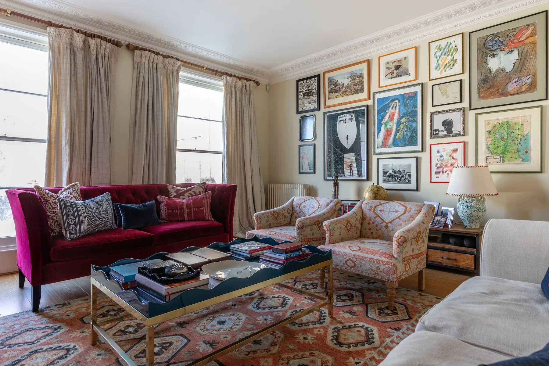 A living room with seating, a glass coffee table, and framed artwork on the walls.