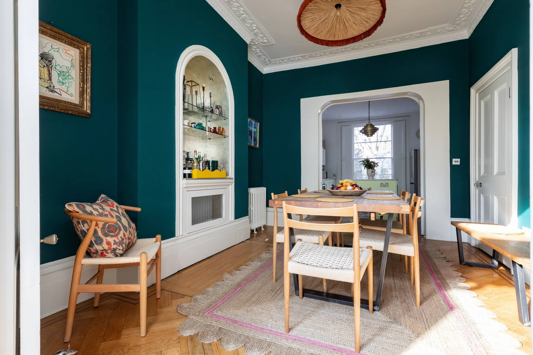 A dining area with a wooden table and chairs beside a built-in display shelf.