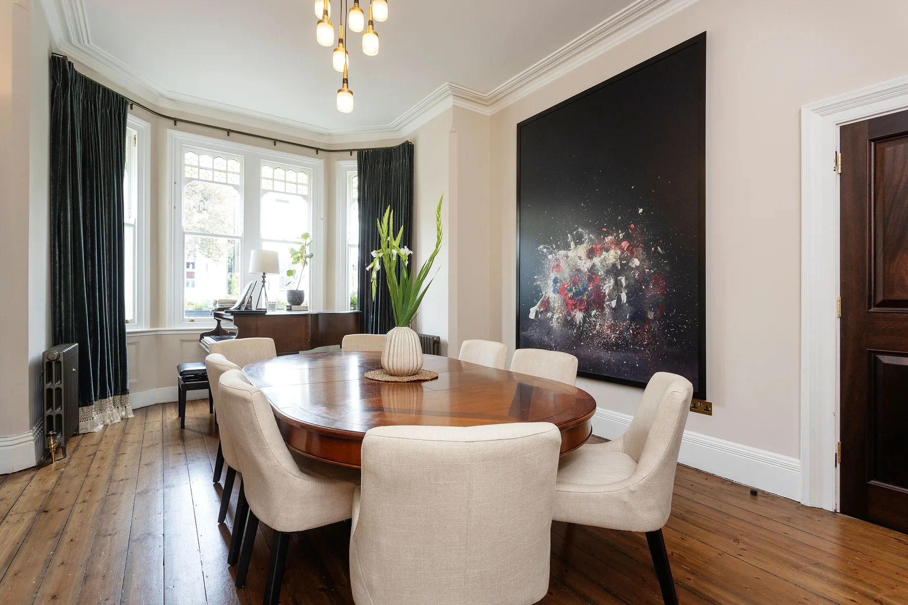 A dining room with a long wooden table surrounded by upholstered seating.