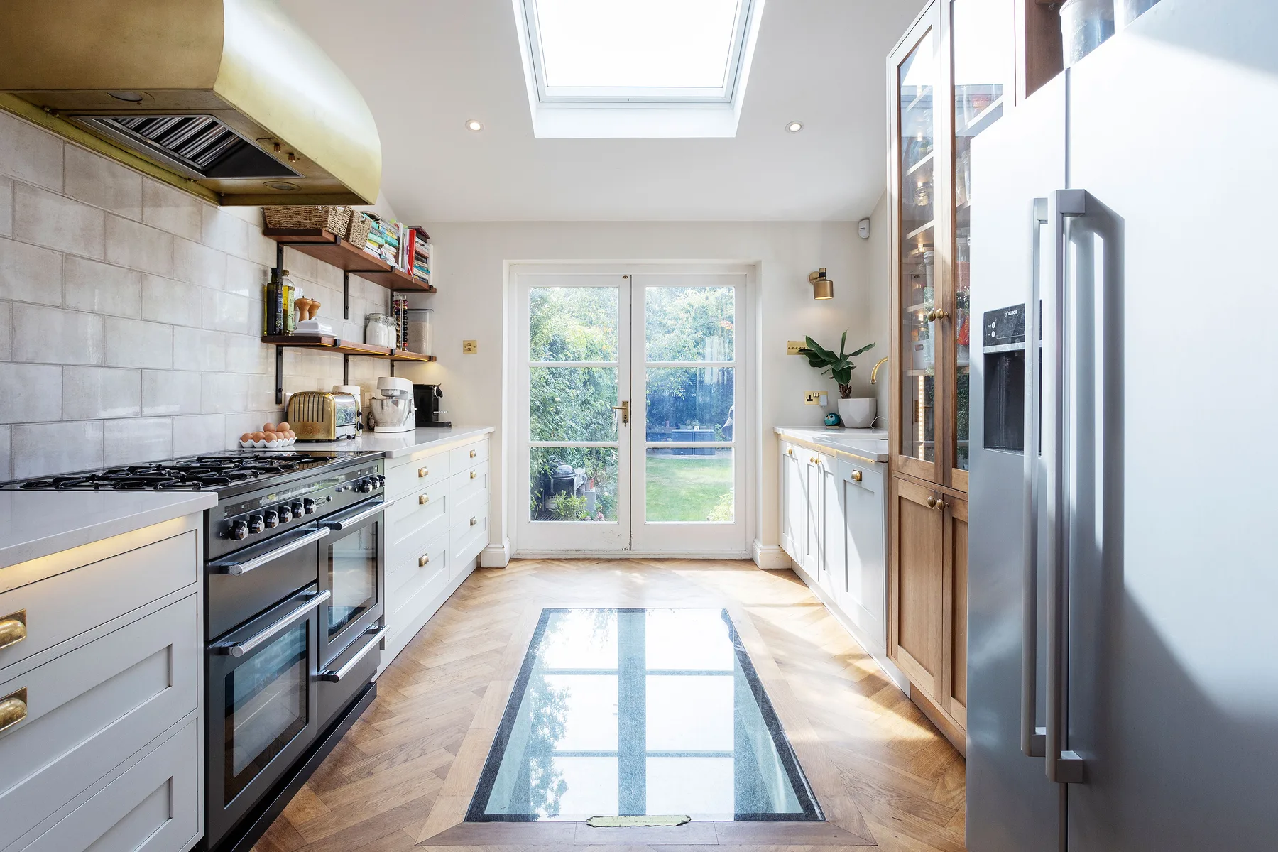 A bright kitchen with white cabinetry, a cooking range, and glass doors.