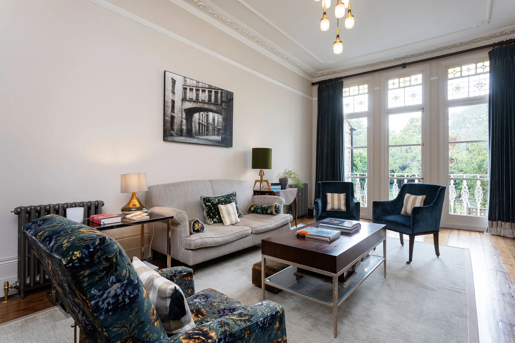 A bright living room has seating arranged around a coffee table beside tall windows.