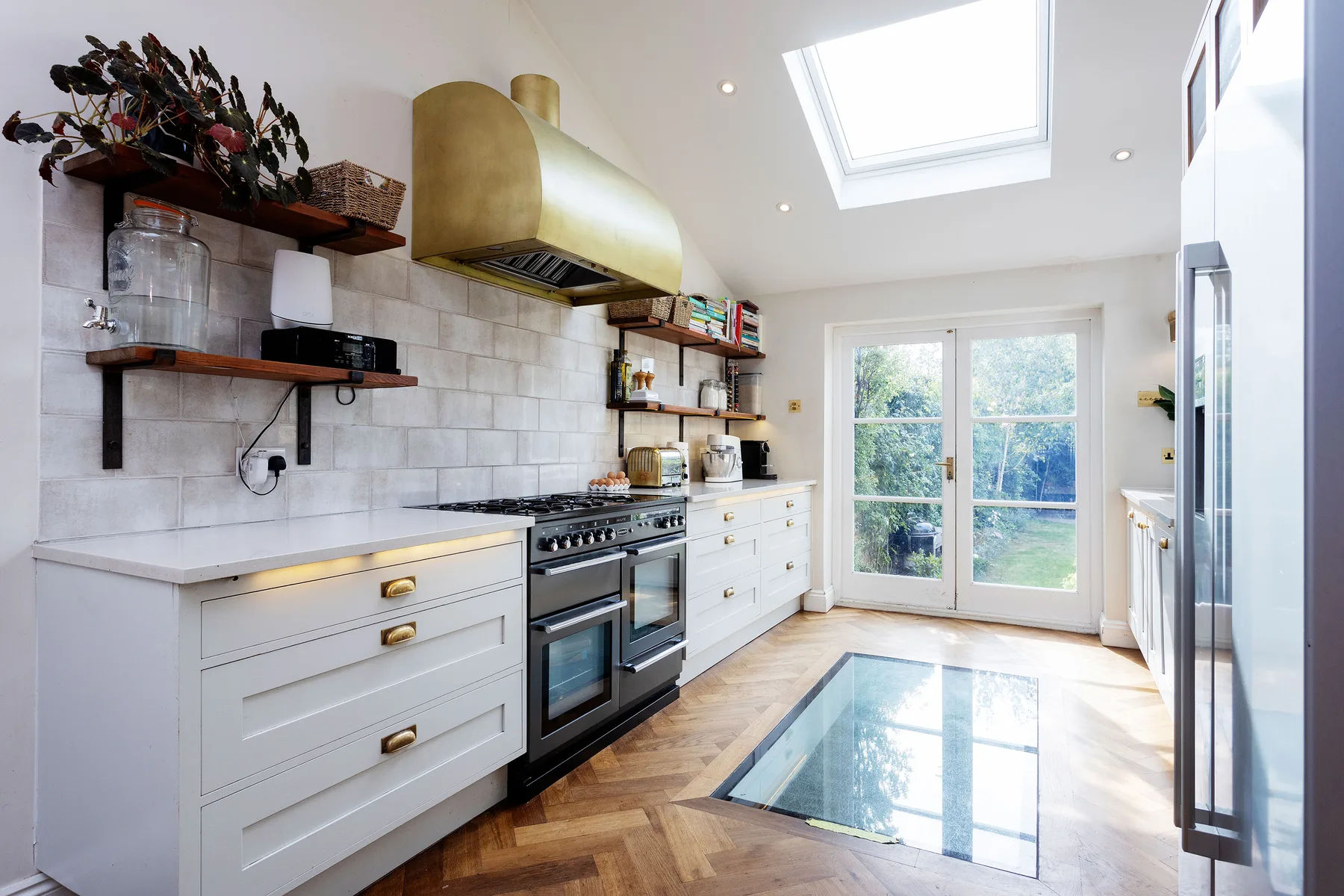 A bright kitchen with white cabinetry, a cooking range, and a glass floor panel.