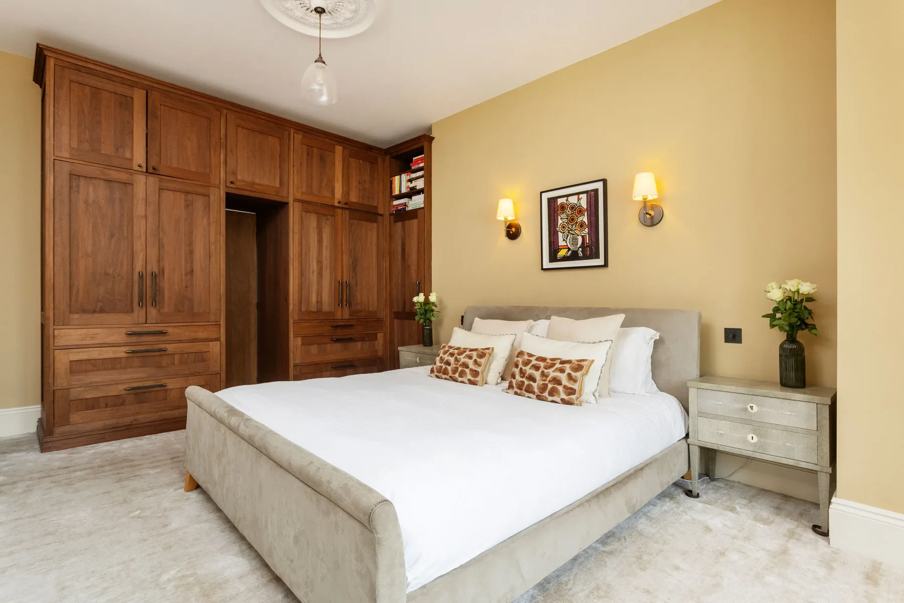 A bedroom with a large bed, built-in wooden cabinets, and bedside tables.