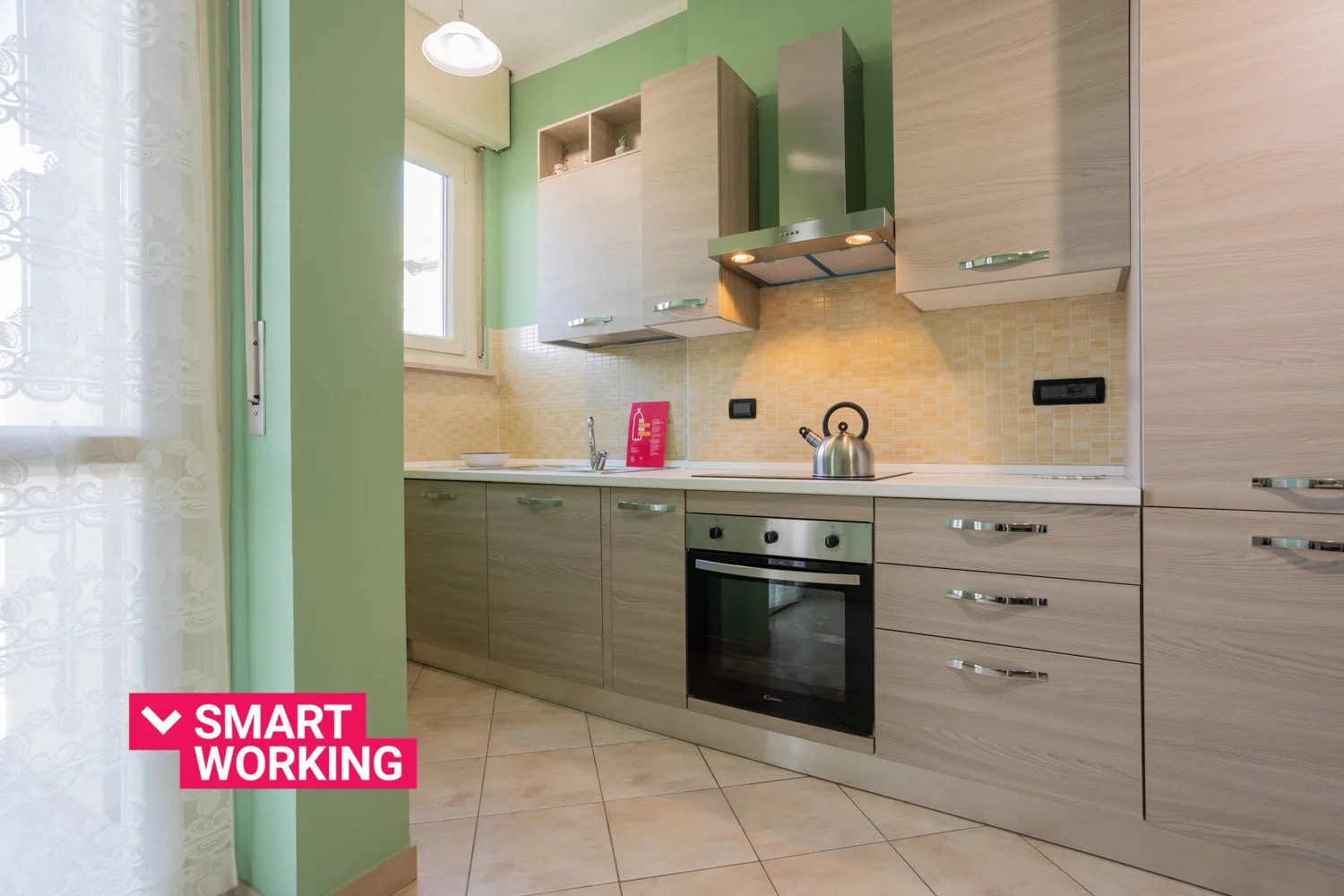A modern kitchen with light wood cabinets and a built-in oven.