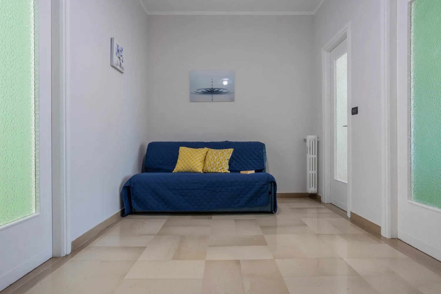 A sitting room with a blue sofa and two yellow cushions.