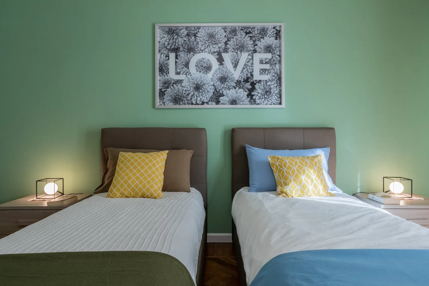 Un dormitorio con dos camas individuales y un cuadro floral enmarcado encima.