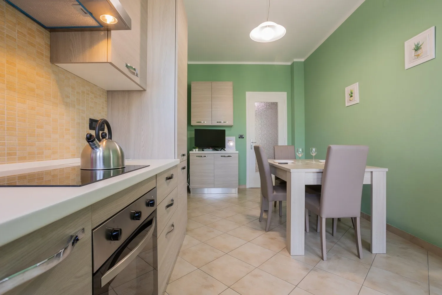 A kitchen and dining area with a counter, table, and green walls.