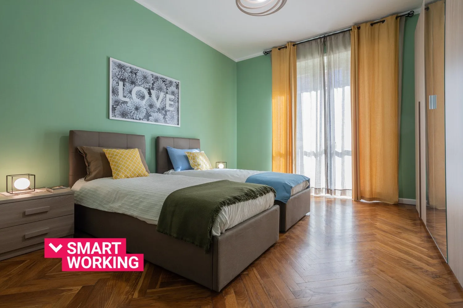 Un dormitorio con dos camas, paredes verdes y cortinas junto a una ventana luminosa.