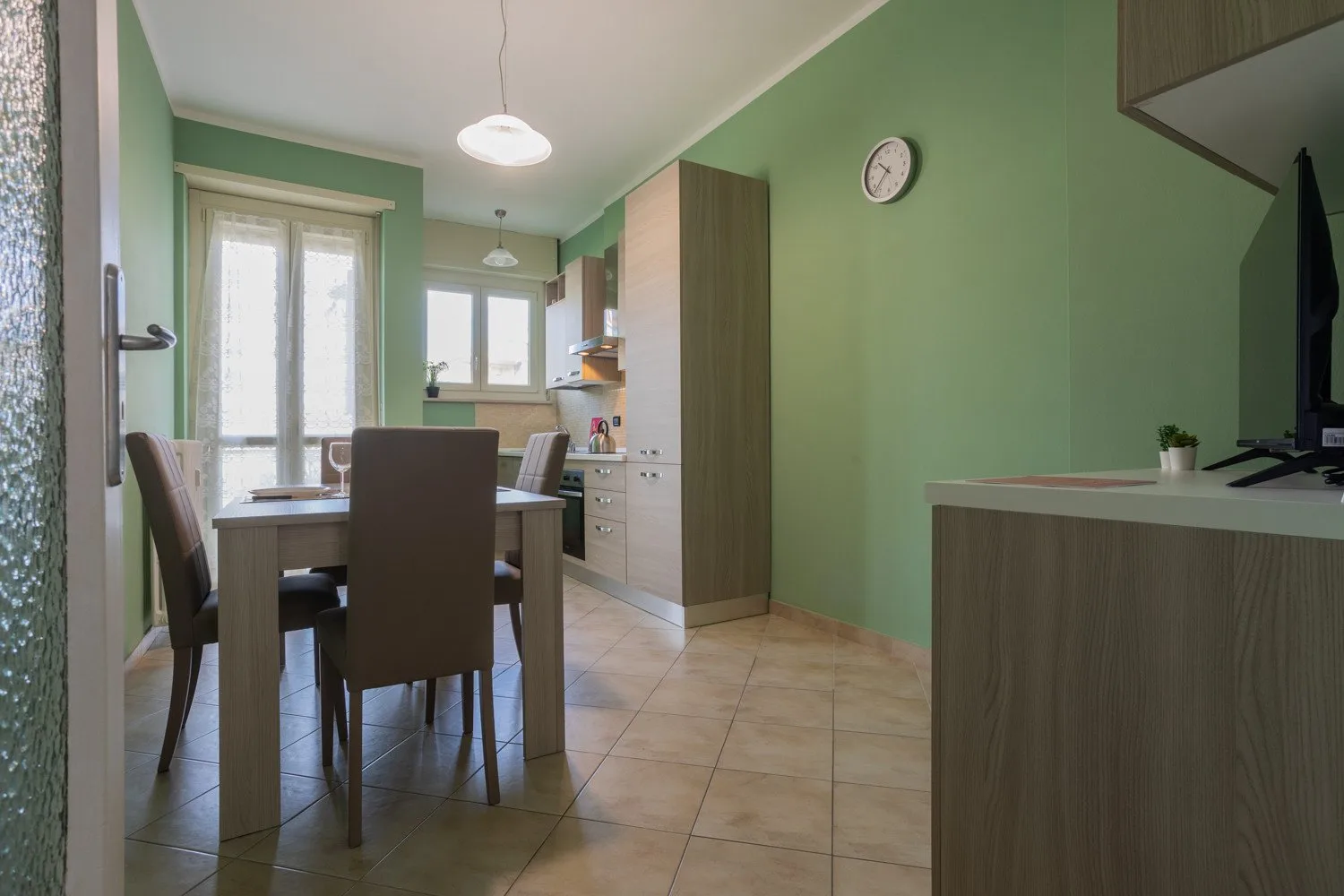 A dining area with a table and chairs beside a compact kitchen.