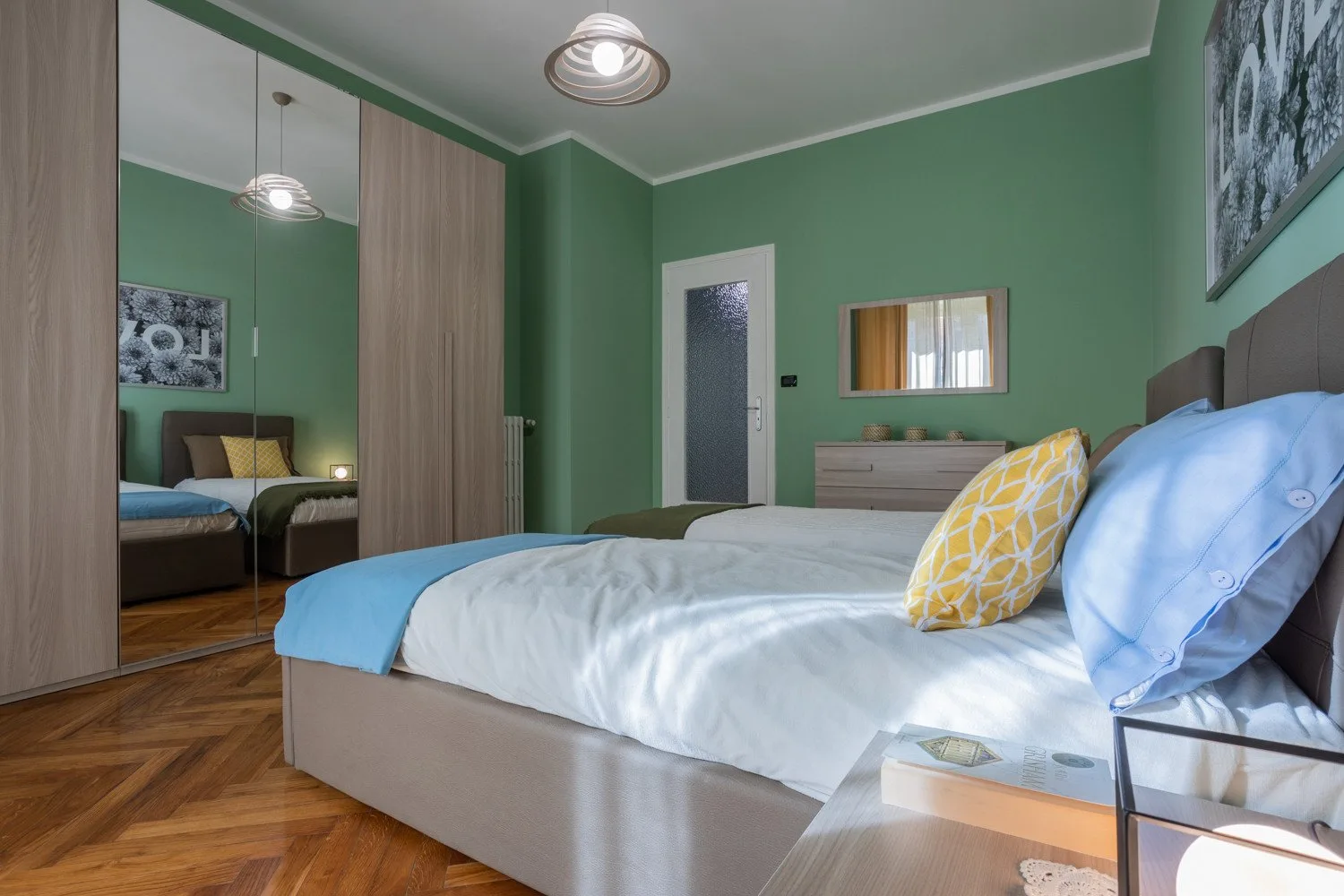 A bedroom with a neatly made bed and green walls.
