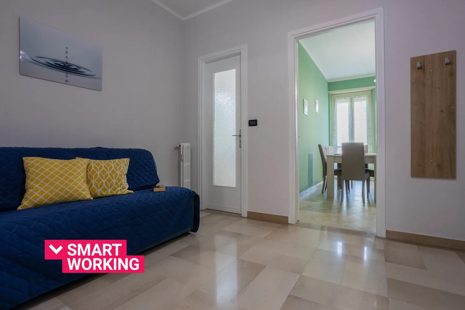 A living room with blue seating and an open doorway to a dining area.