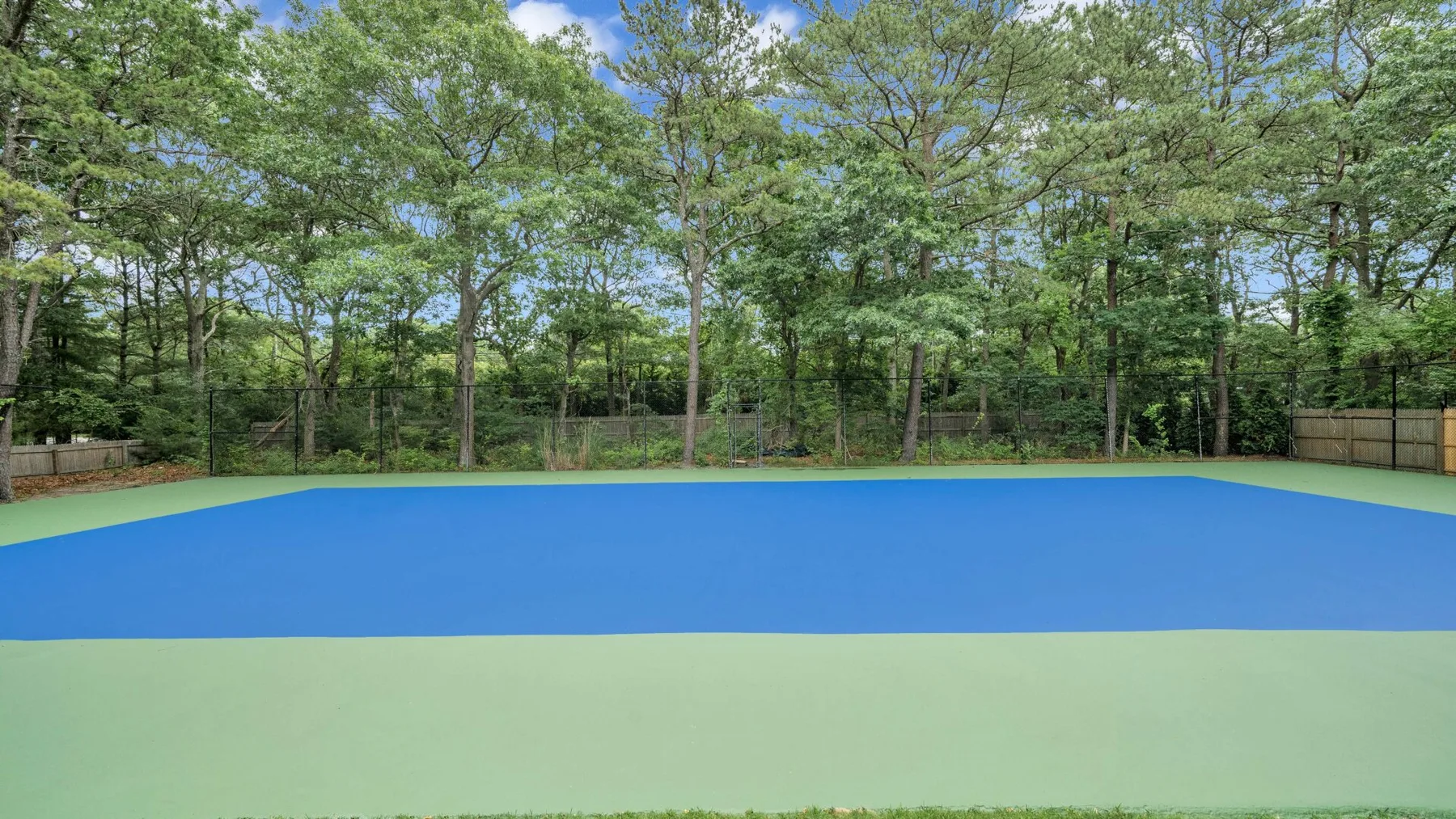 Una cancha exterior azul está rodeada de árboles.