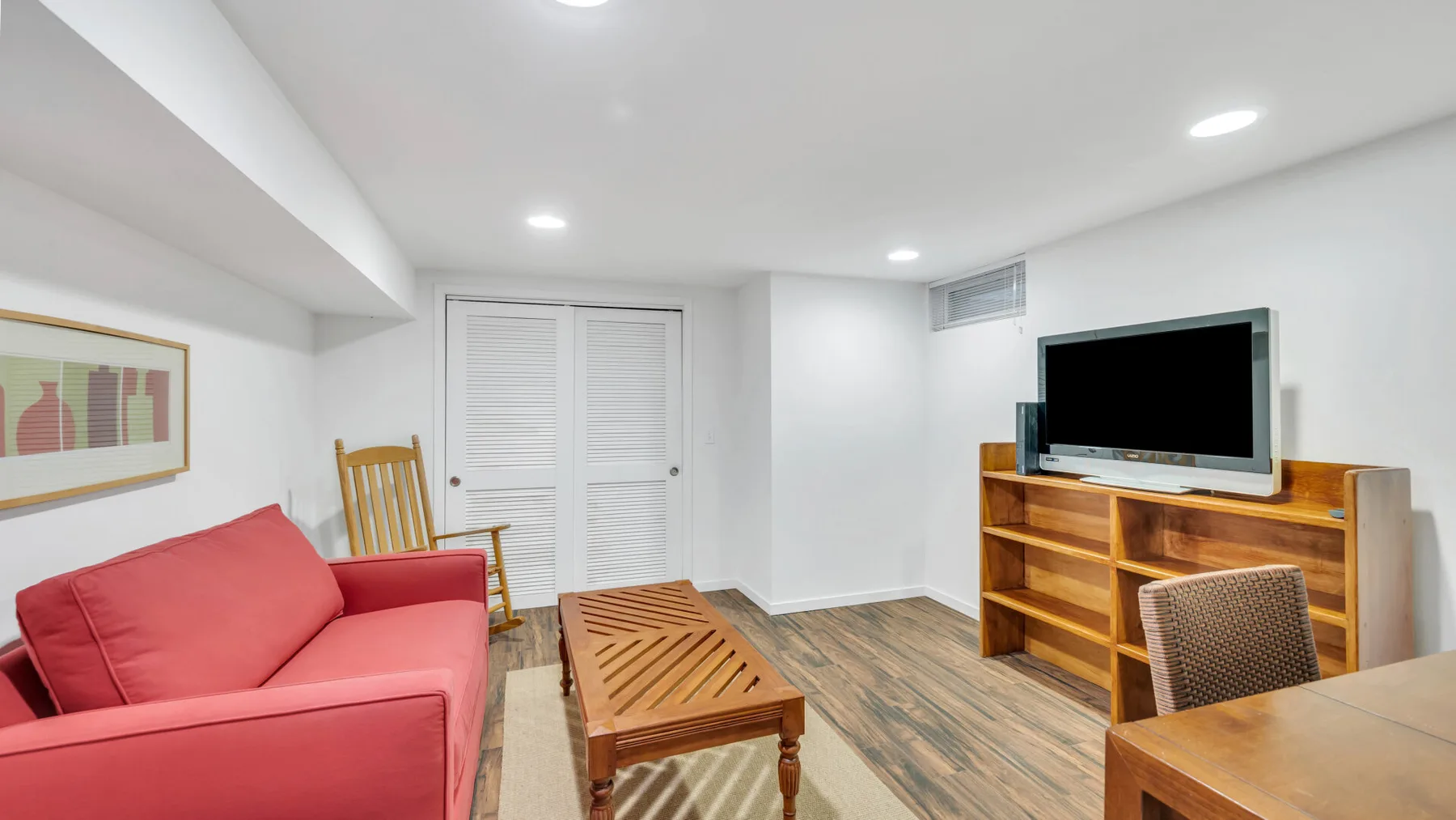 Una sala de estar con un sofá rojo, una mesa de centro de madera y un televisor.