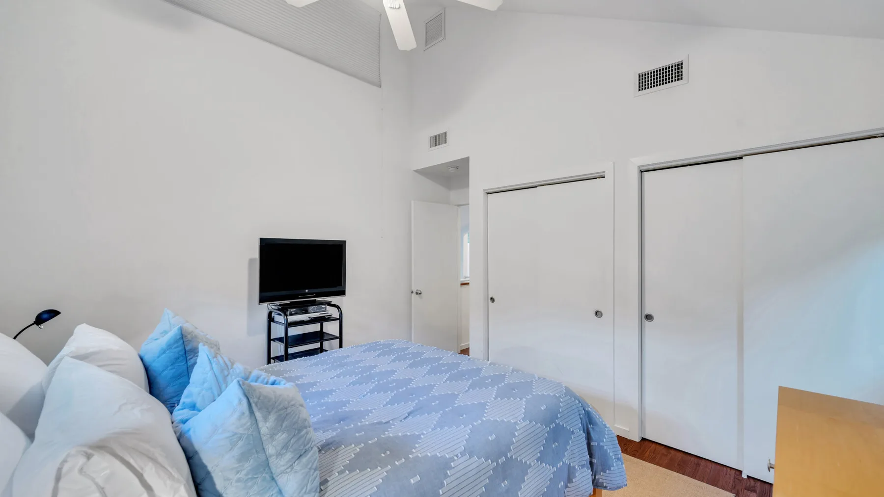Un dormitorio con una cama cubierta con ropa de cama azul estampada y un televisor.