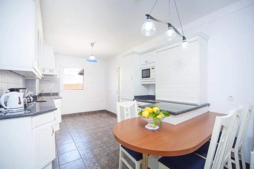 A bright kitchen with white cabinetry and a dining table.