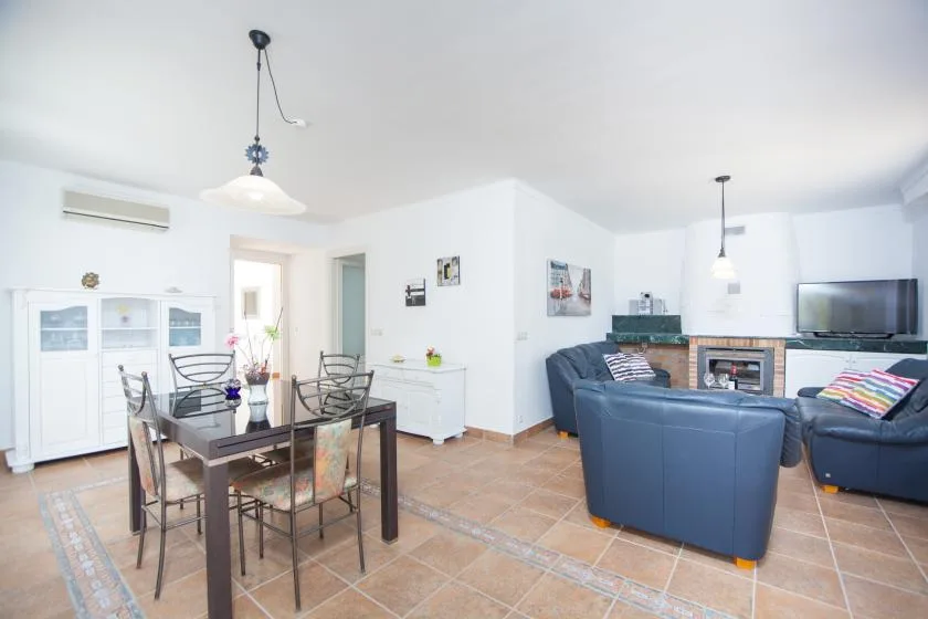 A bright open-plan living and dining room with a dark dining table and blue seating.