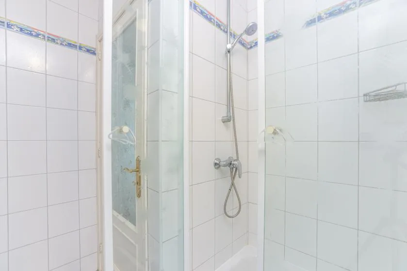 A tiled bathroom with a shower and glass enclosure.