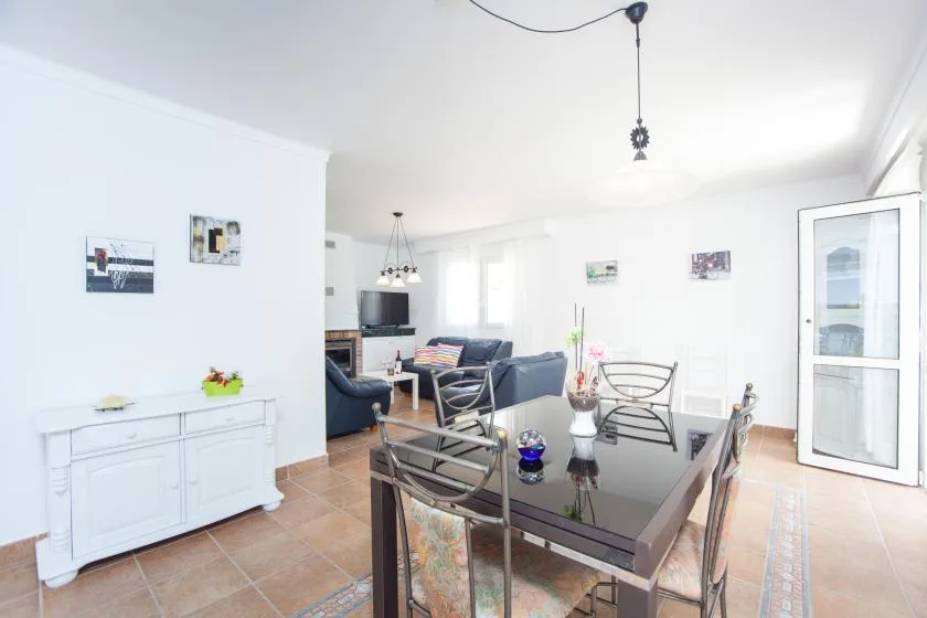 A bright living and dining room with a glass-topped table and seating.