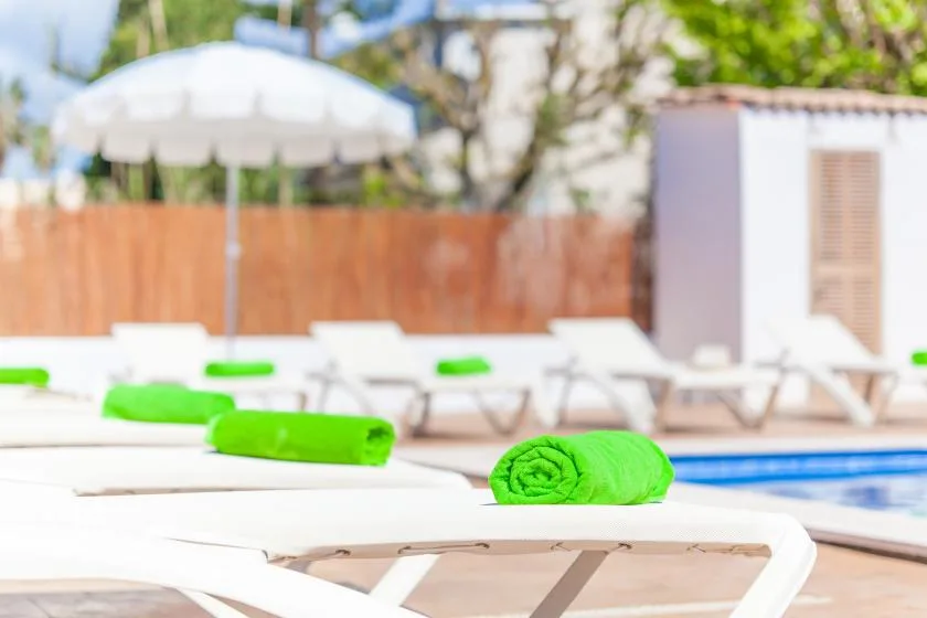 Poolside loungers with bright green towels sit beside the swimming pool.