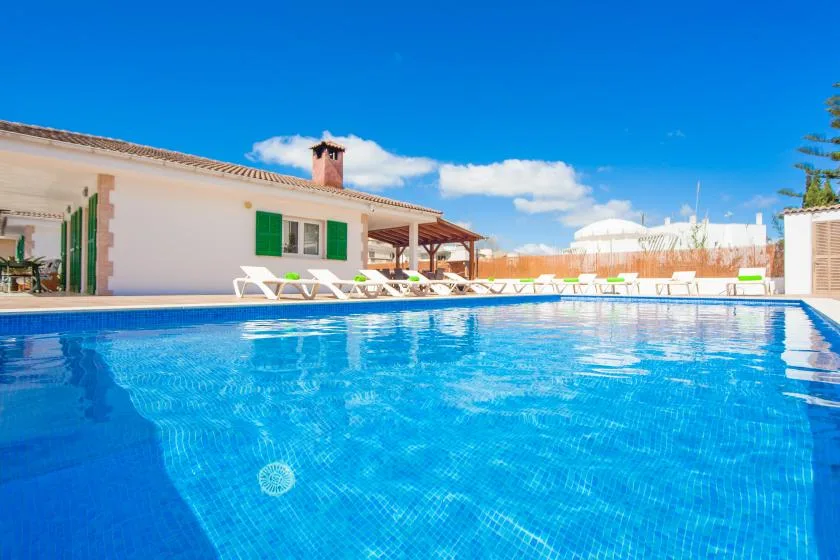 An outdoor swimming pool beside a white building with green shutters.