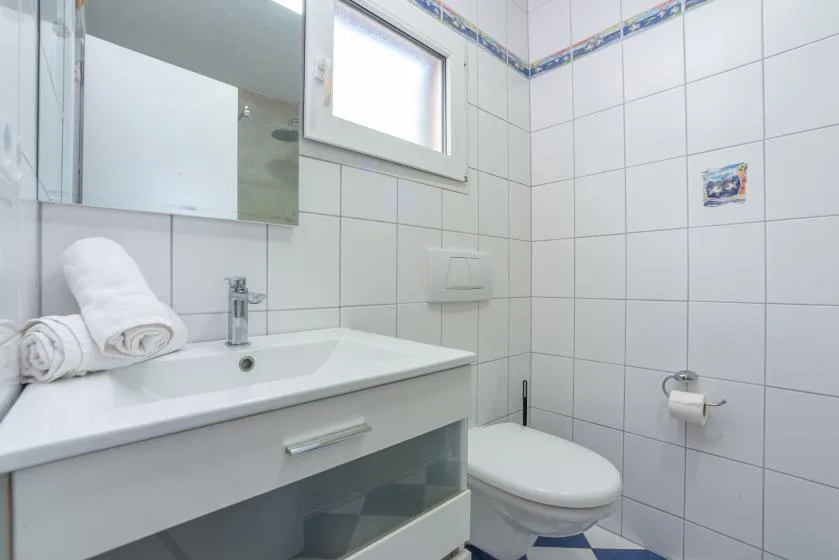 A tiled bathroom with a sink, mirror, and toilet.
