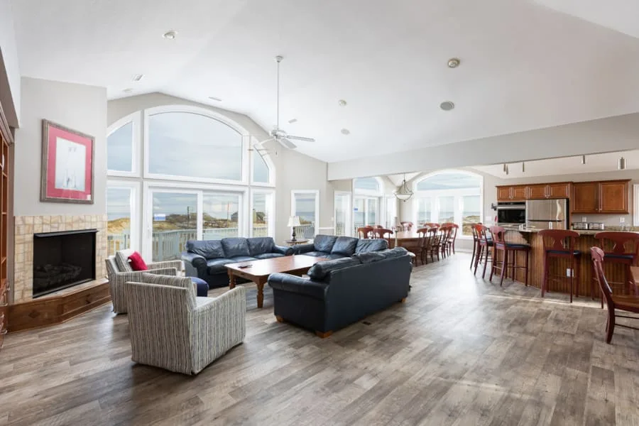 A bright open-plan living room and kitchen with large windows and seating.