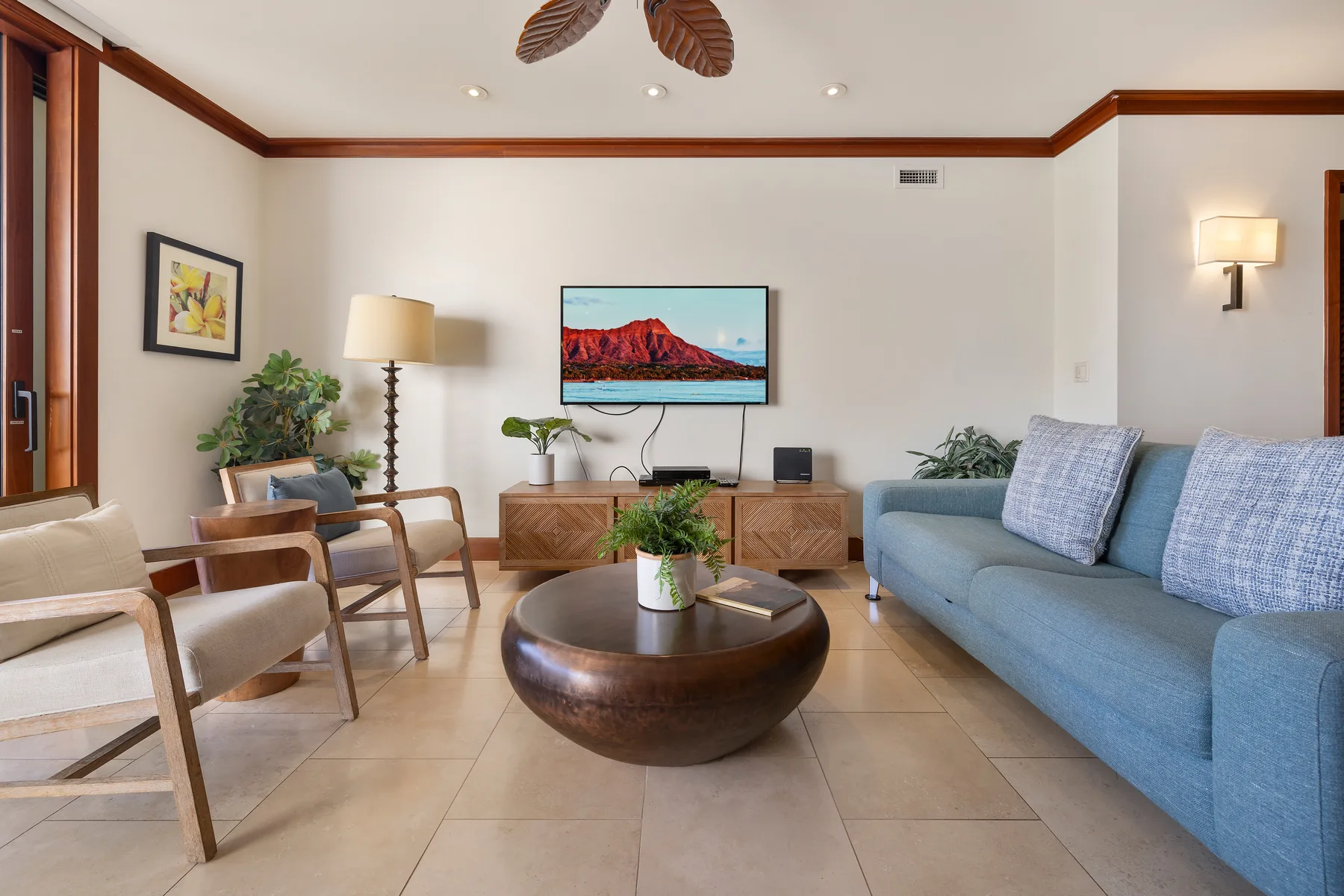 Una sala de estar con asientos alrededor de una mesa de centro y un televisor en la pared.