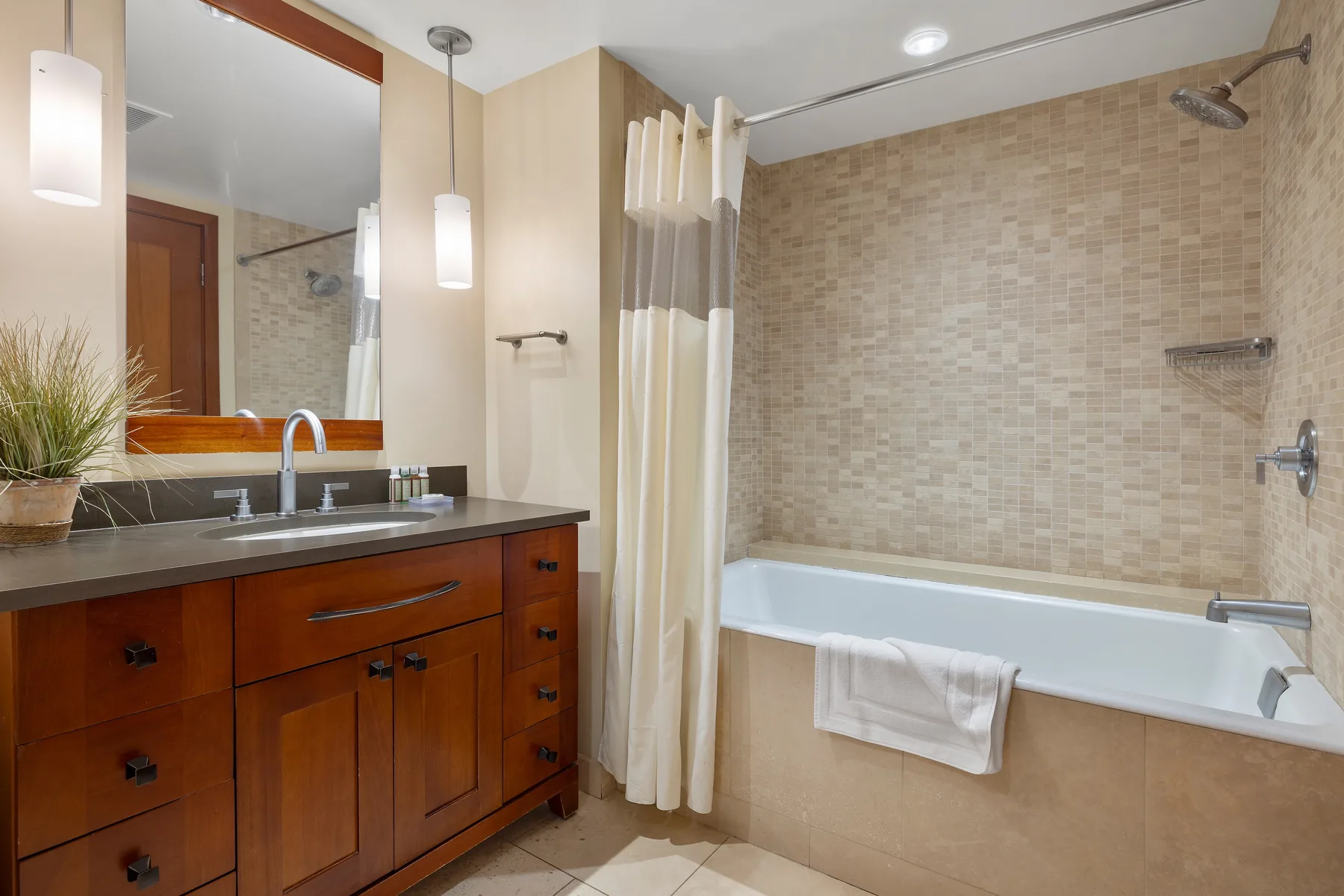Un baño con un tocador de madera y una bañera detrás de una cortina de ducha.