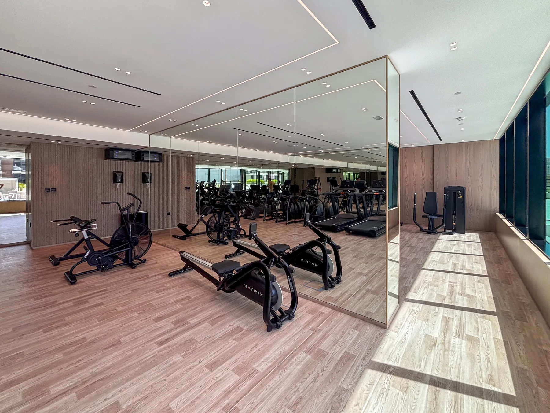 A fitness room with exercise bikes and strength-training equipment beside mirrored walls.