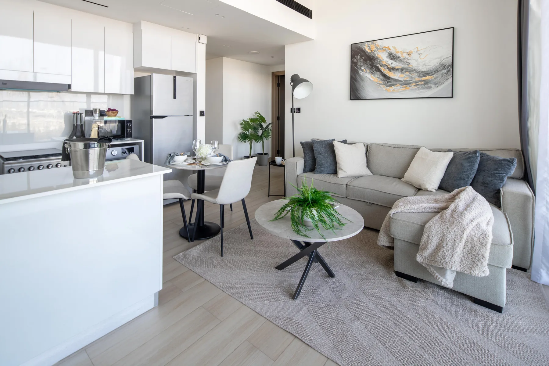 Una luminosa sala de estar con cocina abierta, asientos y una mesa de comedor.