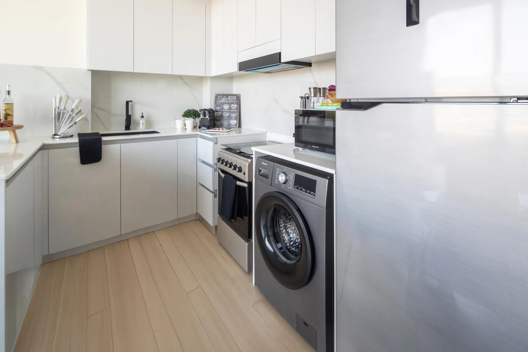 A compact kitchen with counters, a stove, and a washing machine.