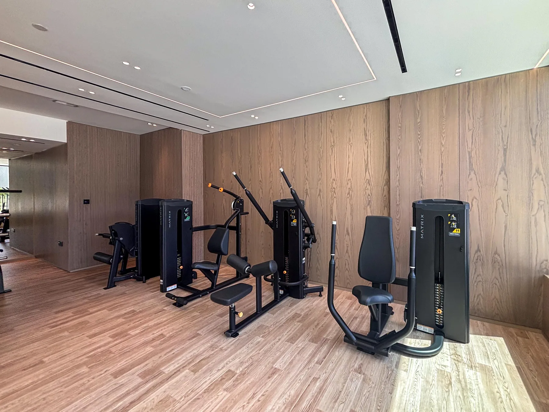 A gym with exercise machines arranged along a wood-paneled wall.