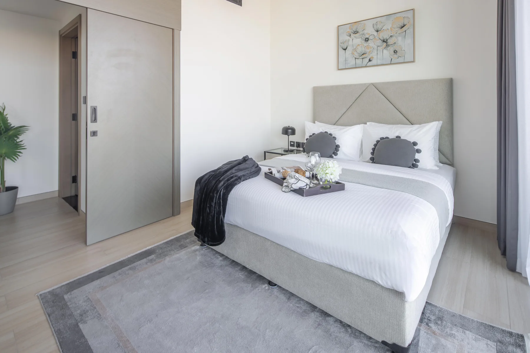 A bedroom with a neatly made bed, decorative pillows, and a rug.