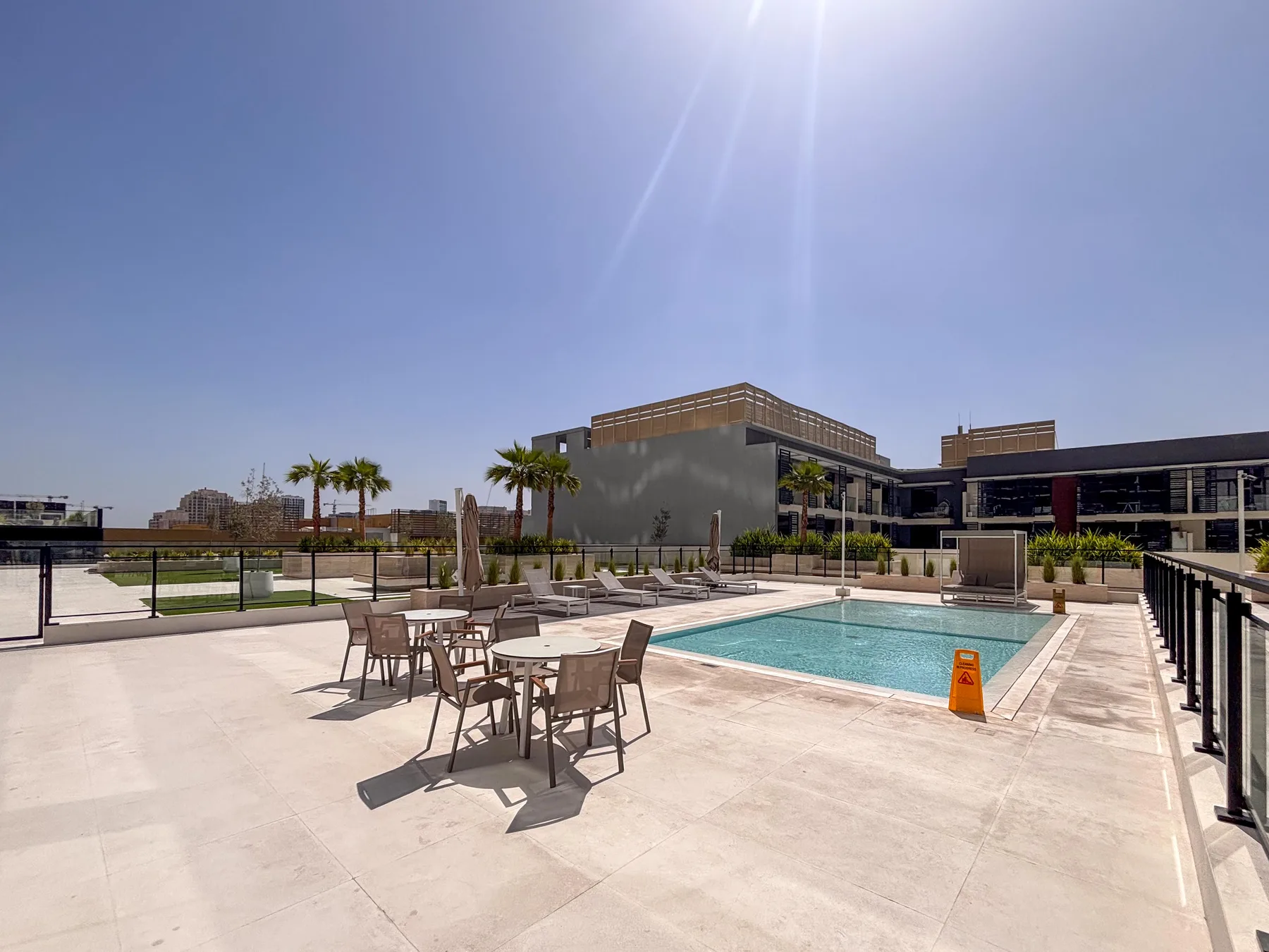 An outdoor pool and patio with tables and seating.