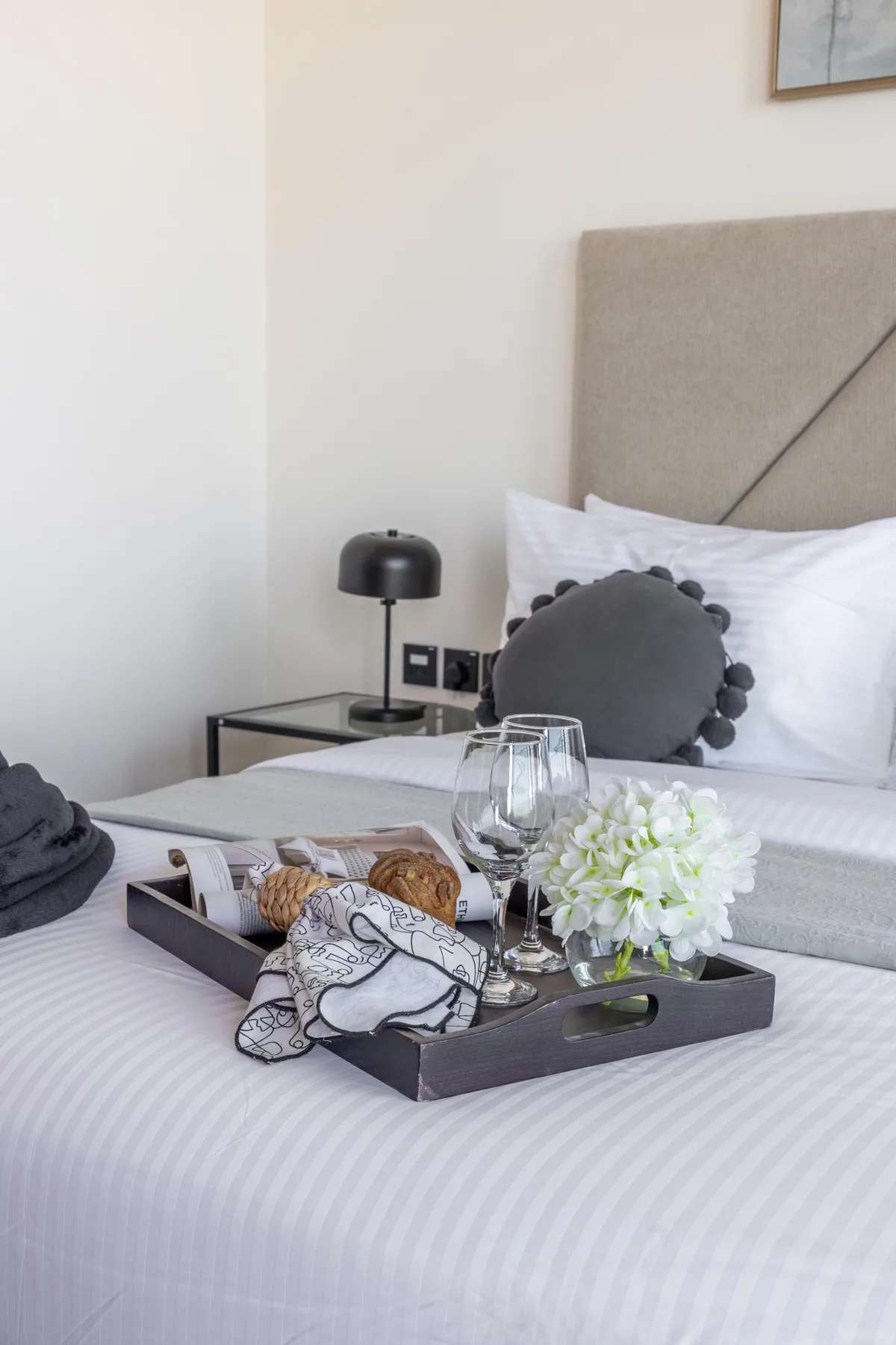 A bedroom with a neatly made bed and a tray of refreshments.