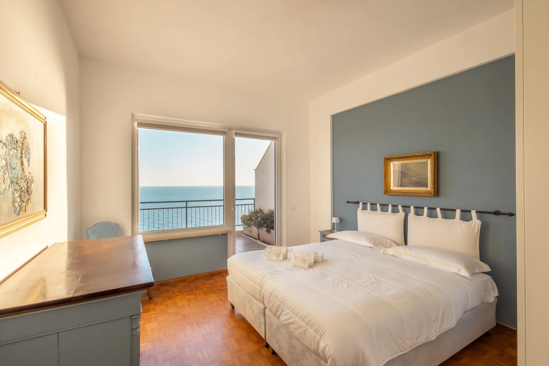 Un dormitorio luminoso con una cama junto a una ventana amplia con vistas al mar.
