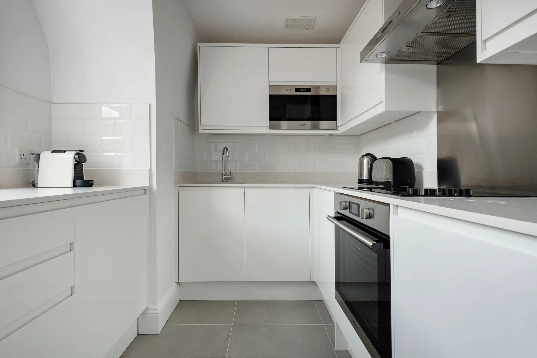 A bright white kitchen with built-in appliances and a tiled backsplash.