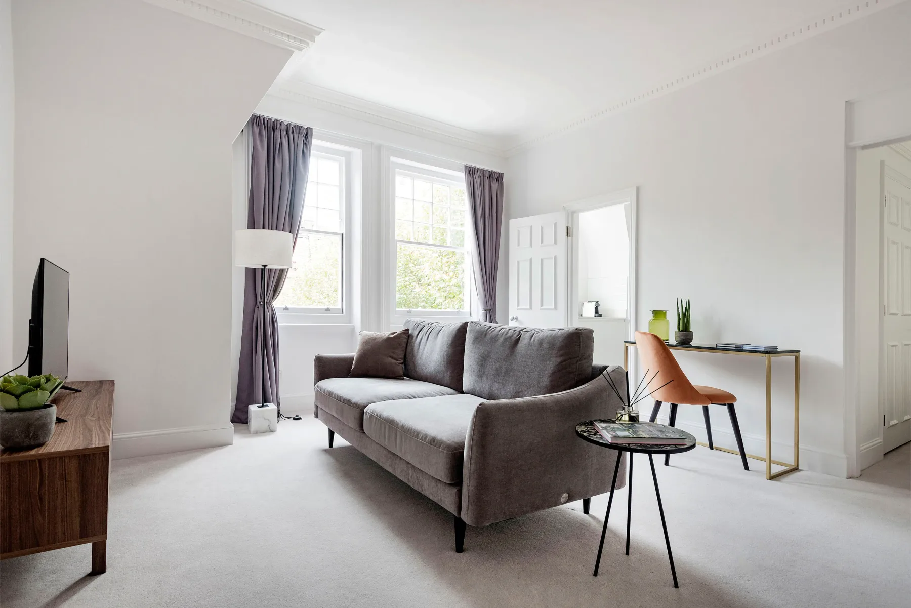 A bright living room with a sofa and tall windows.