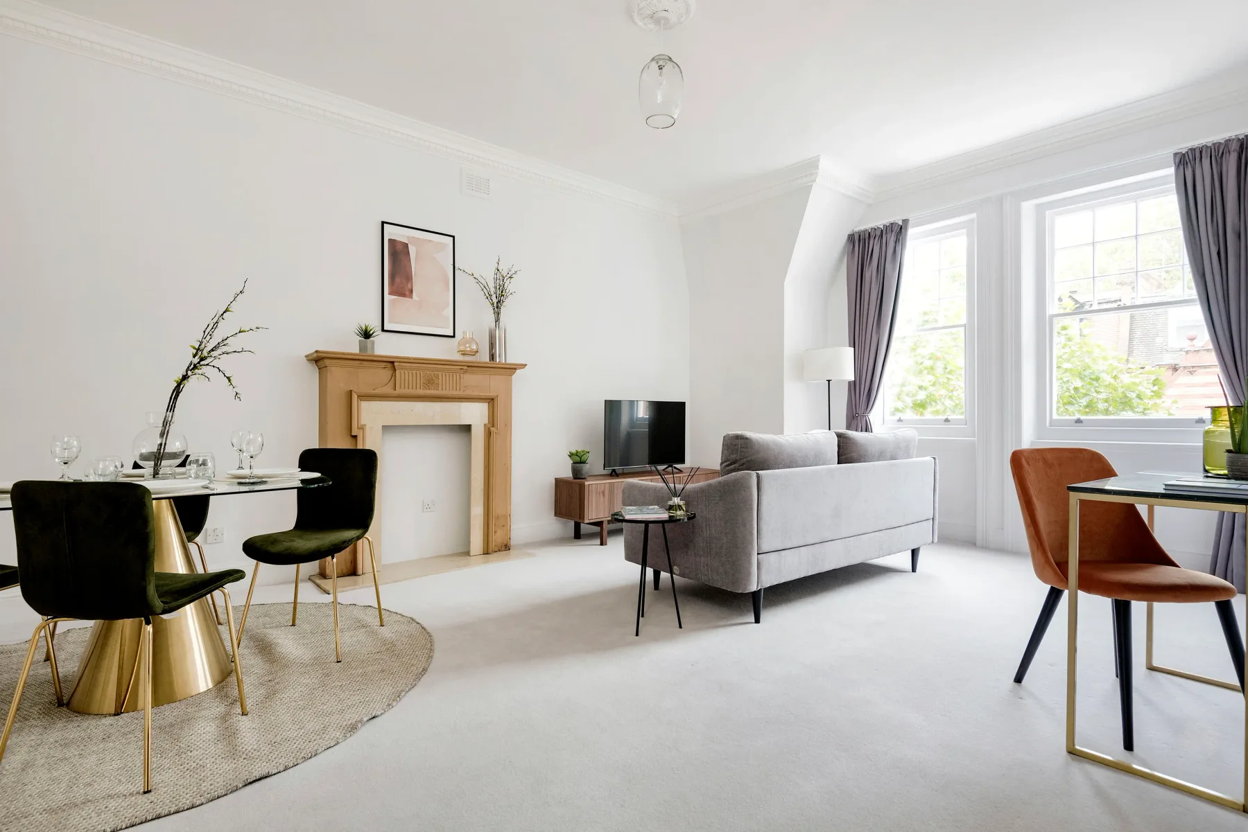 A bright living room with seating, a fireplace, and large windows.