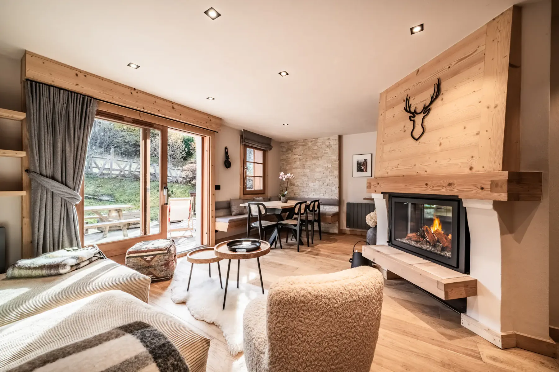 Cozy living room with wooden walls, a staircase, white sofas, a fireplace, and a large photo of a snowboarder on the wall.