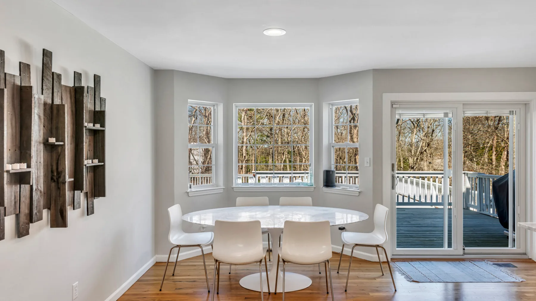 A bright dining area with a round table beside windows and sliding glass doors.