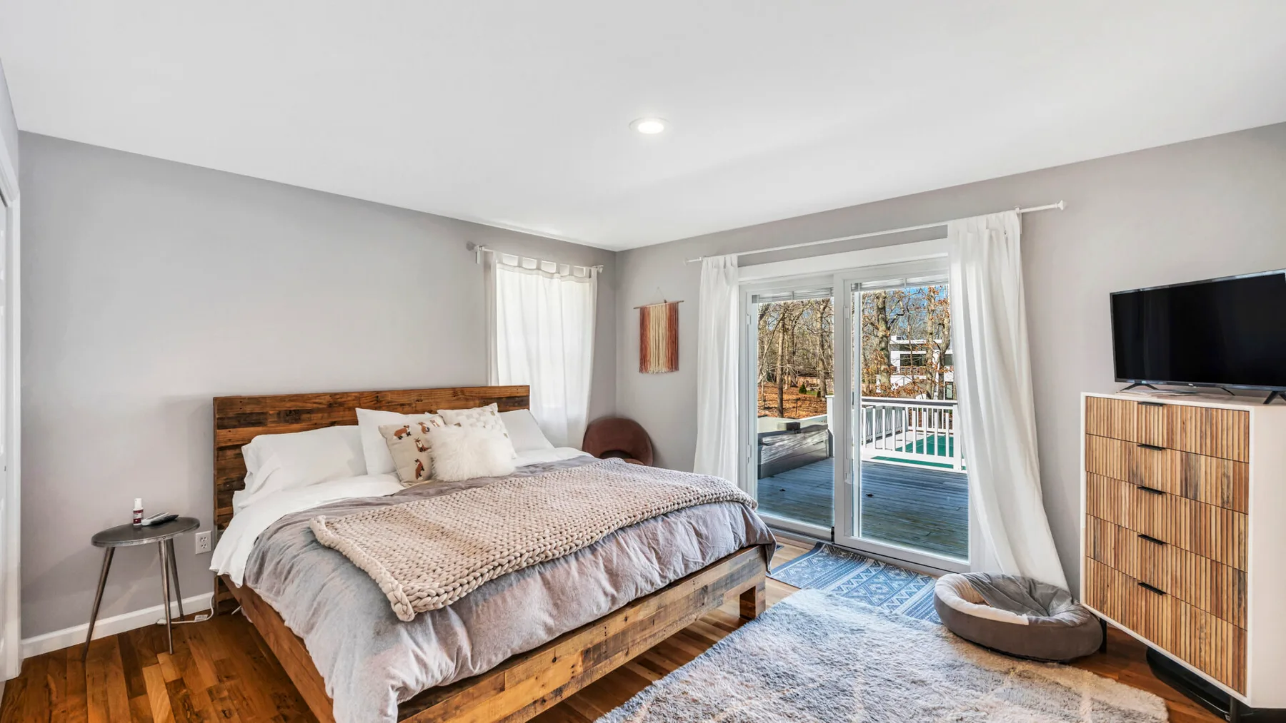 A bedroom with a wooden bed, bedside table, and glass doors opening onto a balcony.